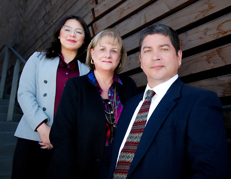 Three professionally dressed individuals posing together indoors.